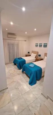 two beds in a large room with blue pillows at Villa Cristina in Quarteira