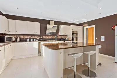 a kitchen with white cabinets and a island with bar stools at Villa Cristina in Quarteira
