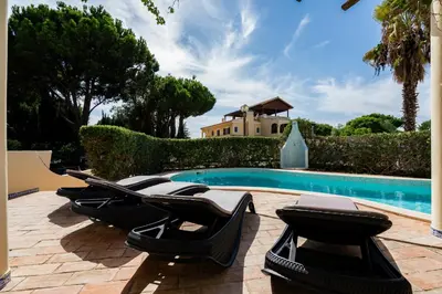 a group of lounge chairs next to a swimming pool at Villa Lucio by SAPvillas in Vilamoura