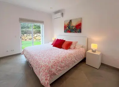 a white bedroom with a bed with red pillows at Beautiful 4-Bedroom Villa with Garden and Pool in Albufeira