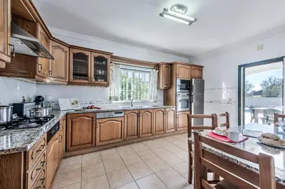 a large kitchen with wooden cabinets and a table at Villa Agapito in Terras Novas