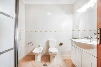 a white bathroom with a toilet and a sink at Villa Alice Albufeira in Albufeira