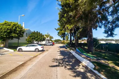 a white car parked in a parking lot next to trees at Ponta Grande Resort - Vila Luzia in Albufeira