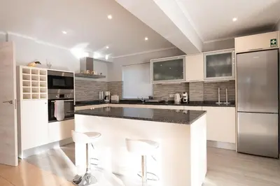 a kitchen with a large island with two bar stools at Villa Louanna in Vilamoura