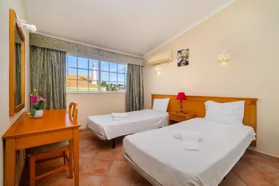 a bedroom with two beds and a desk and a window at Ponta Grande Resort - Villa Atlântica in Albufeira