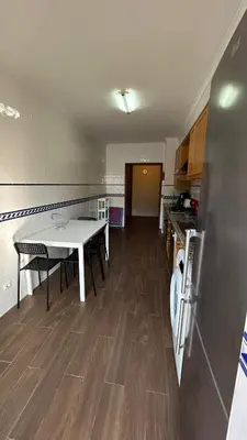 a kitchen with a table and a refrigerator at Pórtico de Malpique in Albufeira