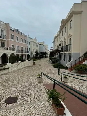 an empty cobblestone street with buildings and plants at Casa Estrelinha Vilamoura in Quarteira