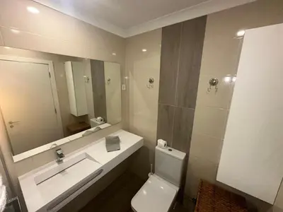 a bathroom with a sink and a toilet and a mirror at Cliff Enchantment - Pool and Sea View in Albufeira in Albufeira