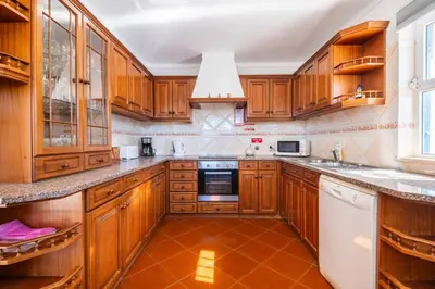 a kitchen with wooden cabinets and a white dishwasher at Villa Gabriella - Charming villa in great location close to everything you need in Guia