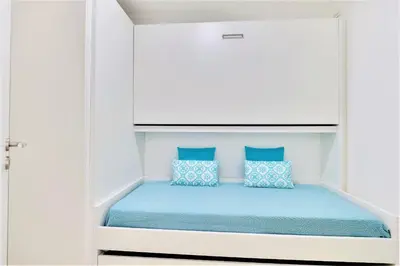 a bed in a white room with blue pillows at Vale do Lobo Apartment in Vale do Lobo