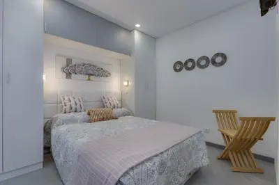 a white bedroom with a bed and a chair at BELLAVISTA STUDIO - Modern and Renovated near Fishermen's Beach in Albufeira