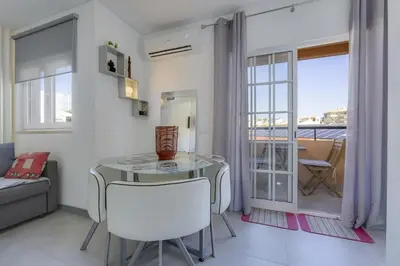 a living room with a glass table and white chairs at BELLAVISTA STUDIO - Modern and Renovated near Fishermen's Beach in Albufeira