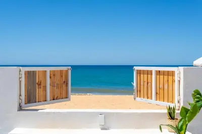 an open door to the beach with the ocean in the background at Beach front right on the Sand Luxury semi-detached 3 bed Villa in Faro