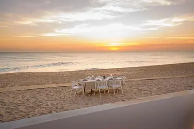 a dinner table on the beach at sunset at Beach front right on the Sand Luxury semi-detached 3 bed Villa in Faro