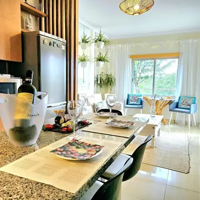 a kitchen and living room with a table with wine glasses at T1 Albufeira Tranquilidade in Albufeira