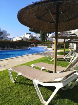 two lounge chairs and an umbrella next to a pool at Solar dos Vilarinhos - By bedzy in Albufeira