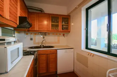 a kitchen with wooden cabinets and a sink and a window at FLH Olhos D' Água Apartment with Pool in Albufeira