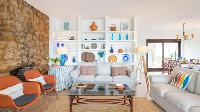 a living room with white furniture and a stone wall at Villa Casa Amendoeiras by LovelyStay in Albufeira