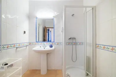 a white bathroom with a sink and a shower at Villa Império in Albufeira