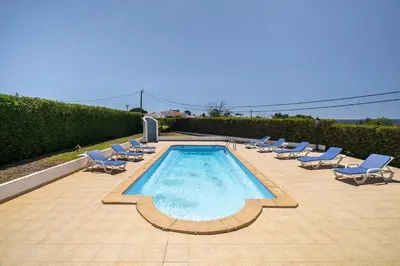 a group of chairs and a swimming pool with chairs at Villa Império in Albufeira