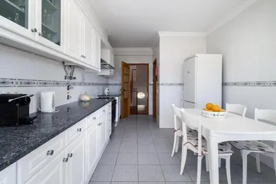 a white kitchen with a table and a white refrigerator at Villa Império in Albufeira
