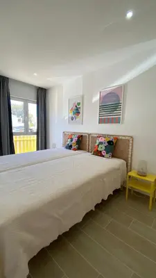 a bedroom with a large bed and a yellow table at Apartamento 5 min a pé da praia, com terraço ao sol, no 1º andar in Quarteira