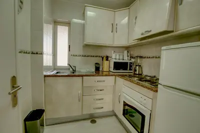 a small kitchen with white cabinets and a sink at Vacation Apartment in Vilamoura in Quarteira
