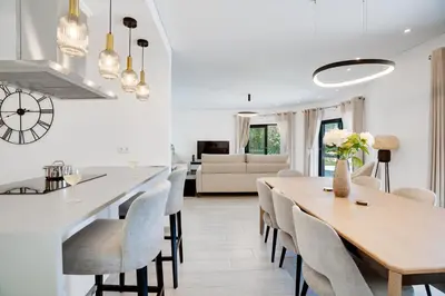 a dining room and living room with a table and chairs at Quinta do Cerro in Loulé