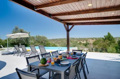 a dining table on a patio with a view of a pool at Quinta do Cerro in Loulé