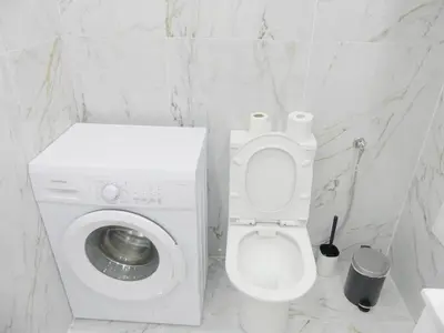 a white bathroom with a toilet and a washing machine at Romao Marina Vilamoura in Quarteira