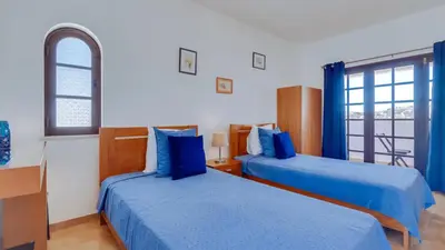 two beds in a room with blue sheets at Villa Rique in Albufeira