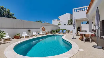 a swimming pool in a yard with chairs and a table at Villa Rique in Albufeira