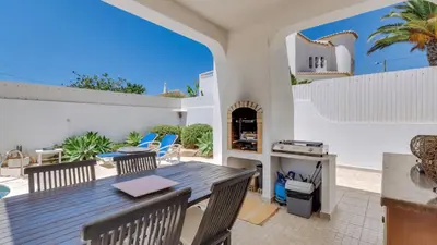 a patio with a table and chairs and a grill at Villa Rique in Albufeira