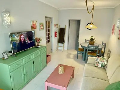 a living room with a couch and a tv on a cabinet at Apartamento Flor de Amendoeira Mar in Albufeira