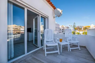a balcony with two white chairs and a table on it at Atlantic Apartment in Albufeira