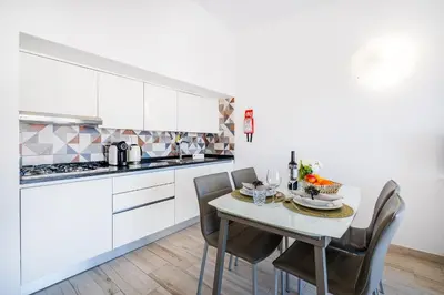 a kitchen with white cabinets and a table with chairs at Atlantic Apartment in Albufeira