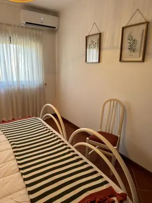 a bedroom with a bed and two chairs and a window at Apartamento Torre da Medronheira in Olhos de Água