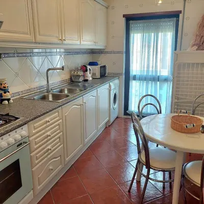 a kitchen with a table and a sink and a table and chairs at Apartamento Torre da Medronheira in Olhos de Água