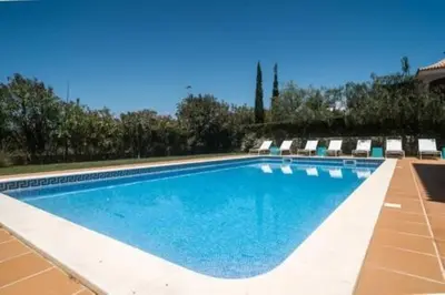 a swimming pool with chairs and blue water at Crest 5 - 8 Pax Golf & Beach Swimming pool in Almancil