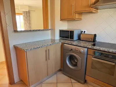 a kitchen with a washing machine and a microwave at Old Village Prestige - Vilamoura in Vilamoura