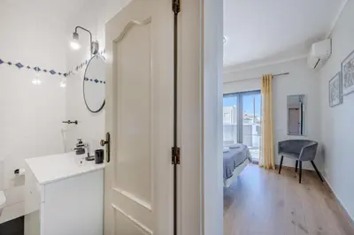 a white bathroom with a sink and a bedroom at Casa Maré Viva in Guia