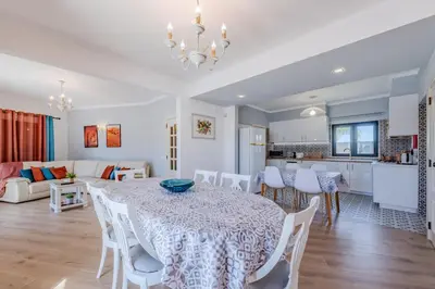 a dining room and living room with a table and chairs at Casa Maré Viva in Guia