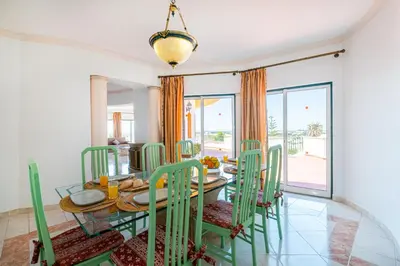 a dining room with a table and green chairs at Villa Atlantida by Atlantic Places in Albufeira