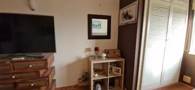 a living room with a flat screen tv and a shelf at Studio on Maria Luisa Beach Wifi Parking Swimming Pool in Olhos de Água