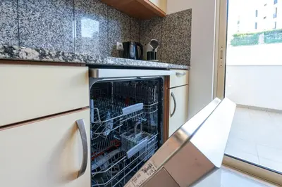 a kitchen with a stove and a washer and dryer at BnB Homes White Rose Garden Apartment with 2 Terraces & 2 Swimming Pools in Albufeira