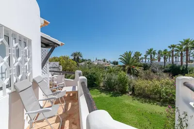 a balcony with white chairs and a yard at Ocean Vista Retreat with Beach & Pool Access by Drago Rentals in Albufeira
