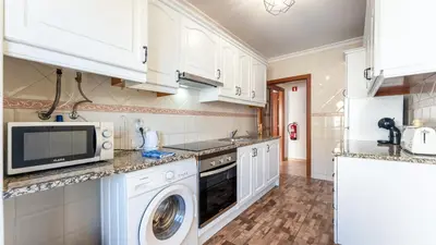 a kitchen with white cabinets and a washer and dryer at Sunny Retreat with Pool and Balcony by LovelyStay in Albufeira