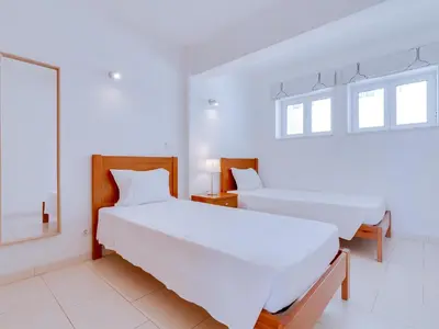a white room with two beds and a mirror at AL - Apartamento Canto do Mar frente à praia in Quarteira
