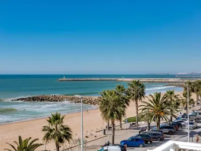 a view of a beach with palm trees and cars at AL - Apartamento Canto do Mar frente à praia in Quarteira