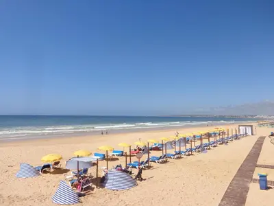 a beach with chairs and umbrellas and the ocean at Sunshine by Check-in Portugal in Albufeira